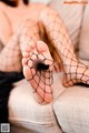 A woman in fishnet stockings is sitting on a couch.