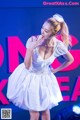 A woman in a white dress standing on a stage.