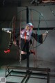 A woman in a black and white outfit is suspended on a swing.