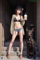 A woman holding a cup of coffee next to a dog.