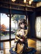 A woman in a kimono sitting on the floor in front of a window.