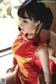 A woman in a red dress sitting on a window sill.